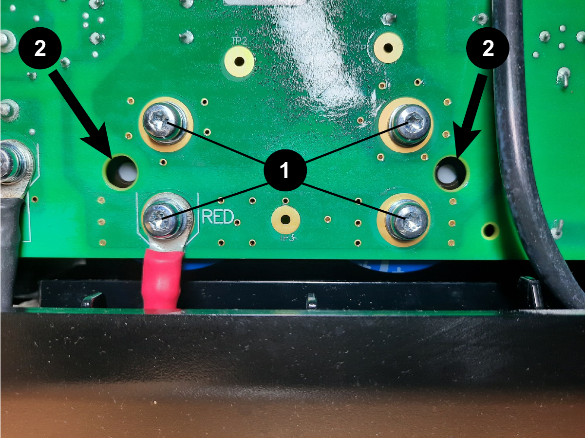 The image shows the capacitor screws and the white dots in the vent holes in the power Printed Circuit Board.